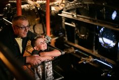 an older man and young boy are looking at something in a metal basket that is on display