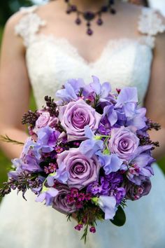 a bride holding a bouquet of purple flowers