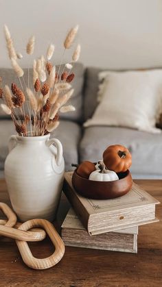 a white vase sitting on top of a wooden table next to a pile of books