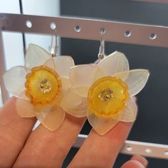 two flower shaped earrings are being held in someone's hand