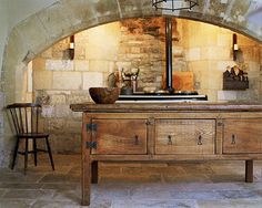 an old wooden table with two chairs and a stove in the middle of a room