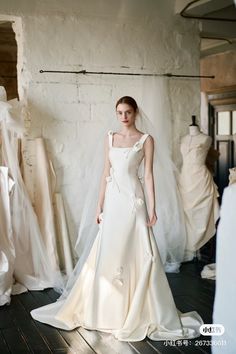 a woman in a white wedding dress standing next to mannequins