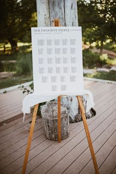 a wooden easel with a white sign on it sitting in front of a tree