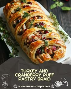 a turkey and cranberry puff pastry braid on a white platter with herbs