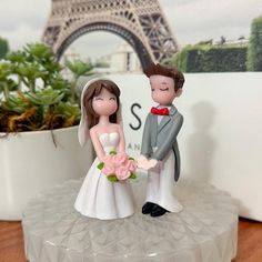 a wedding cake topper with the eiffel tower in the background