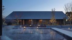 a house with a pool in front of it and lit up lights on the windows