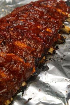 ribs covered in barbecue sauce sitting on top of aluminum foil with seasoning sprinkles