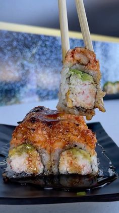 two pieces of sushi sitting on top of a black plate