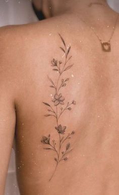 the back of a woman's body with flowers on her left shoulder and right arm