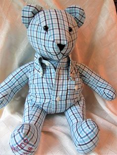 a blue and white plaid teddy bear sitting on a bed