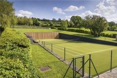 an aerial view of a tennis court surrounded by trees and bushes on a sunny day