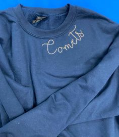 Show your Comets Spirit with this Comets Sweatshirt! This Embroidery is sewn in a handstitched font around the collar of the sweatshirt. There are 2 sweatshirt styles: A crew neck cropped sweatshirt.  A classic crewneck sweatshirt. On Navy and Blue sweatshirts, the thread will be gold On White sweatshirts, the thread will be blue Pick Up at ICS ONLY. Shipping not available. Varsity Sweatshirt With Custom Embroidery For Fall, Fall Tops With School Spirit Letter Embroidery, Fall School Spirit Embroidered Sweatshirt, School Spirit Embroidered Tops For Fall, School Spirit Tops With Embroidered Text For Fall, Fall School Spirit Tops With Embroidered Text, Fall Tops With Embroidered Text For School Spirit, Varsity Crew Sweatshirt With Embroidered Text, Fall College Sweatshirt With Embroidered Text