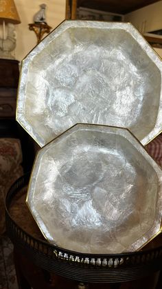 two white plates sitting on top of a wooden table next to a chair and mirror