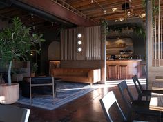 an empty restaurant with tables and chairs in the center, near a bar that has plants growing out of it