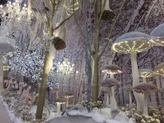 a room filled with lots of trees covered in lights and snow next to a wall