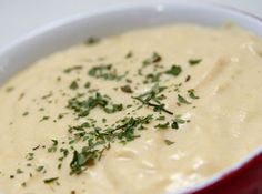 a red and white bowl filled with soup on top of a table