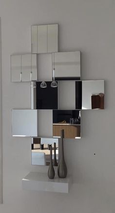 a white shelf with mirrors and vases on it