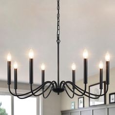 a black chandelier with six candles hanging from it's center and four lights on each end