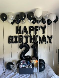 black and white balloons are on the wall above a bed with a 21st birthday sign