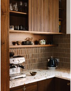 a kitchen with wooden cabinets and white counter tops, coffee maker on the left side