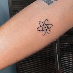 a person's arm with a tattoo on it that has an atomic symbol in the middle