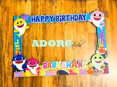 a happy birthday photo frame with baby shark and other cartoon characters around it on a wooden surface