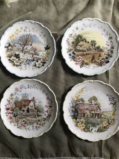 four plates with different designs on them sitting on a tablecloth covered surface, one has a house and the other is a farm