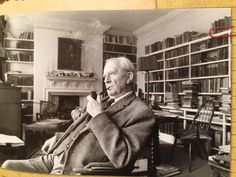 an old black and white photo of a man sitting in a chair talking on a phone