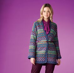 a woman standing in front of a purple background wearing a colorful coat and matching pants