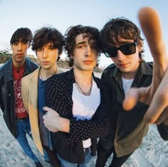 four young men standing next to each other in front of the camera with their fingers up