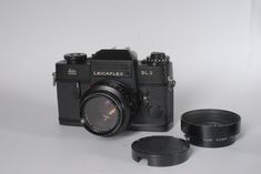 an old camera and lens cap sitting next to each other on a white table top