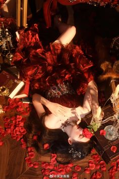 a woman laying on the floor surrounded by red flowers