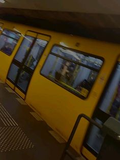 a yellow subway car with its doors open and people walking on the platform next to it