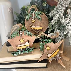 three wooden ornaments on top of a book next to a christmas tree and potted plant