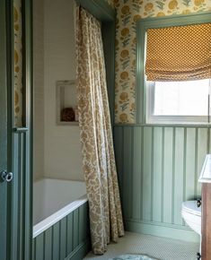 a bath room with a toilet and a tub next to a window in the wall