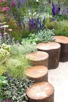 several wooden logs stacked on top of each other in the middle of a garden area