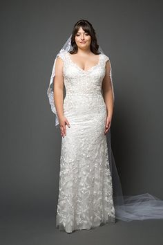 a woman in a wedding dress with a veil on her head standing against a gray background