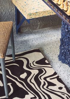 a table with chess pieces on it in front of a rug and chair next to the table