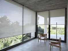 an empty room with two chairs and large windows