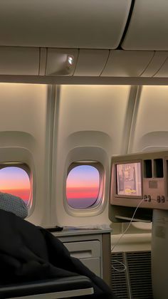 the view from inside an airplane looking out at the sunset through the window and on to the back of the seat