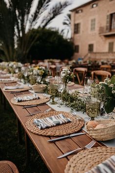 a long table is set up with place settings and flowers on it for an outdoor dinner