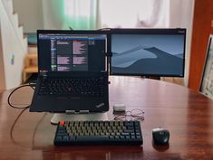 a laptop computer sitting on top of a wooden desk next to a keyboard and mouse