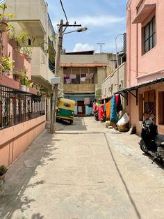 a narrow street lined with parked motor scooters and clothes hanging out to dry