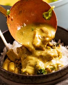 a wooden spoon scooping some food out of a bowl filled with rice and broccoli