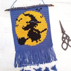 a crocheted wall hanging with scissors next to it