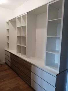 an empty room with white shelves and wooden floors