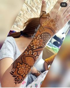 a woman is holding her hand up to show the henna tattoo on her arm