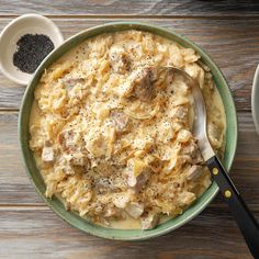 a bowl filled with pasta and meat on top of a wooden table