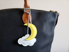 a black purse with a yellow moon and cloud on it