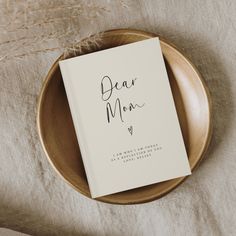 a book sitting on top of a wooden plate next to a plant and dried grass